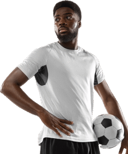 Hombre afrodescendiente vistiendo camiseta deportiva gris sosteniendo un balón de fútbol, posando con una expresión decidida.